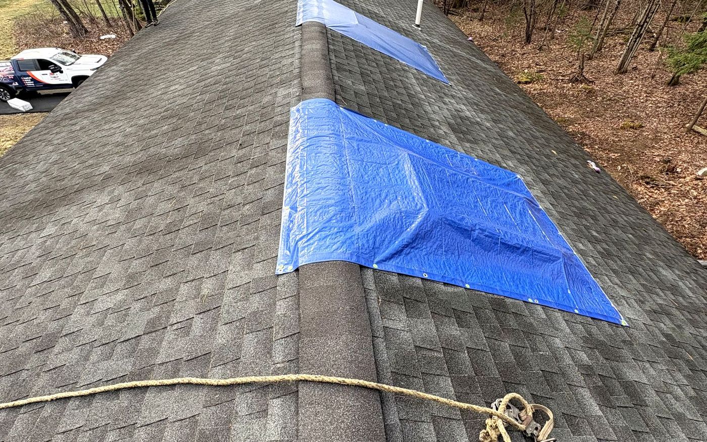 Storm-damaged roof under emergency tarps before A-Z Roofing replacement