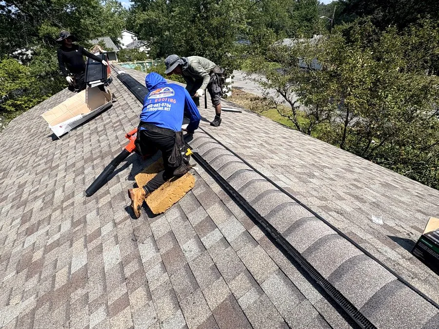 Roofer repairing shingles beside a skylight